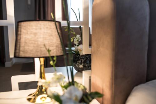 a table with a lamp and flowers on it at Hotel Boavista in Timişoara