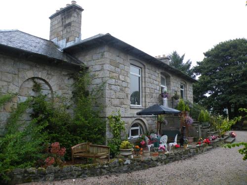 a stone house with an umbrella in front of it at Disblair House in Newmachar