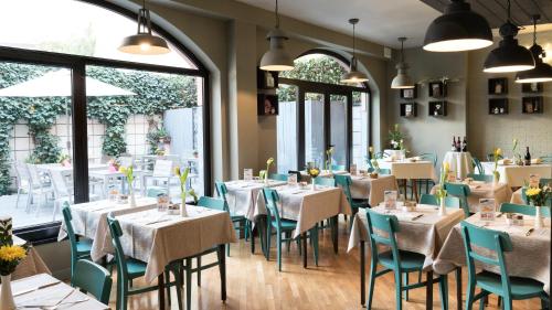 a dining room with tables and chairs and windows at Hotel Lombardia in Milan