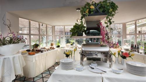 a restaurant with white tables and plates and flowers at Hotel Lombardia in Milan