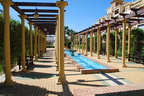 een rij zuilen met een zwembad onder een paviljoen bij Canela Park by Ĥ in Isla Canela