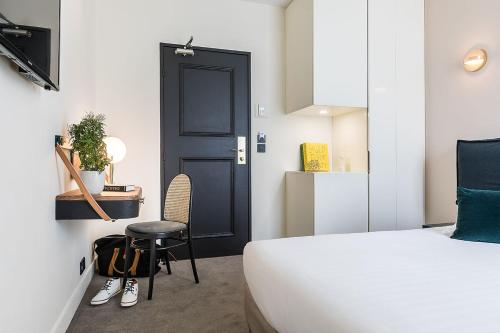 a bedroom with a bed and a black door and a chair at Hotel Le Friedland in Paris