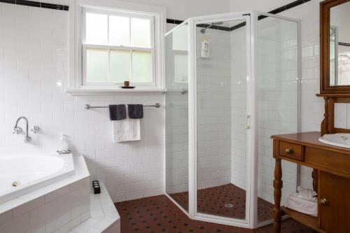 a white bathroom with a shower and a sink at Clare Valley Heritage Retreat in Clare