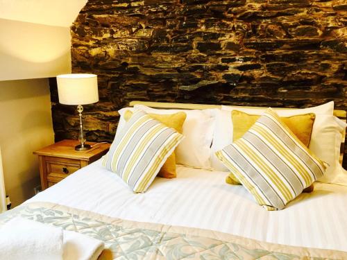 1 dormitorio con cama con almohadas y pared de piedra en Honeypot Cottage in Centre of Bowness, en Bowness-on-Windermere