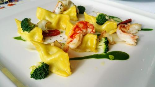 a white plate of food with shrimp and broccoli at Hotel Arnika Wellness in Passo San Pellegrino