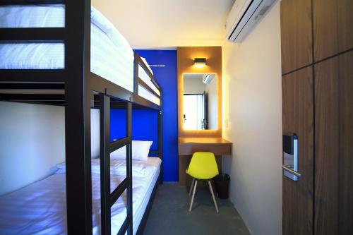 a bedroom with two bunk beds and a yellow chair at Tuk Tuk Hostel in Bangkok