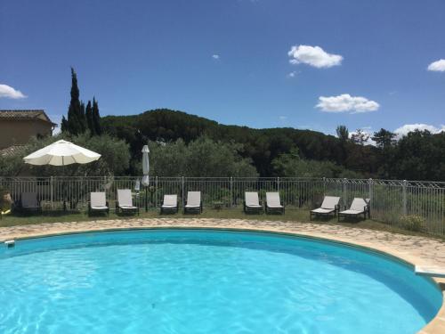 une piscine avec des chaises longues et un parasol dans l'établissement Lourmarin,Domaine de Casteuse Appartement LES OLIVIERS, à Lourmarin