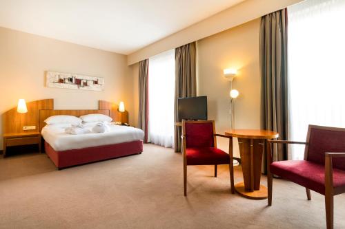 Habitación de hotel con cama, mesa y sillas en Astoria Hotel Antwerp en Amberes