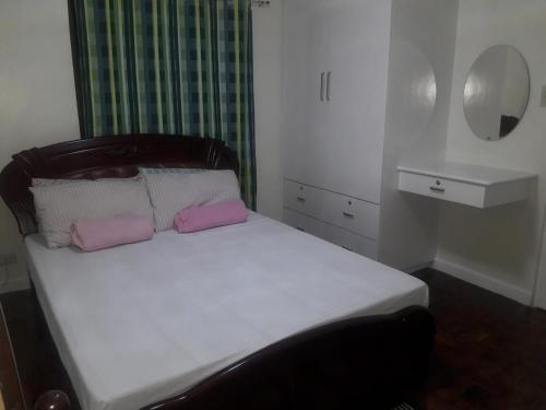 a bedroom with a bed with two pink pillows at Golden Queen Suites in Baguio