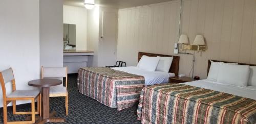 Habitación de hotel con 2 camas, mesa y silla en Mountain View Inn Yreka CA, en Yreka