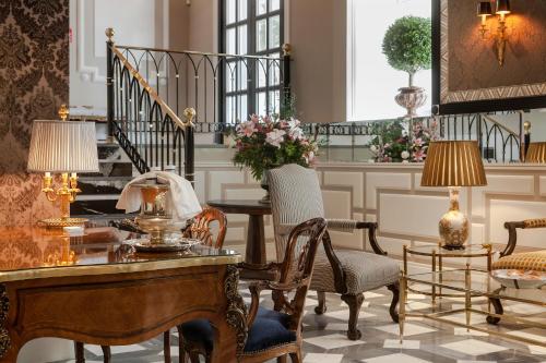 ein Wohnzimmer mit einem Tisch, Stühlen und einer Treppe in der Unterkunft Relais & Châteaux Heritage Hotel in Madrid