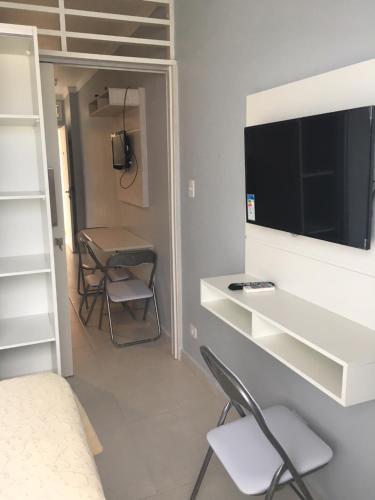 1 dormitorio con 1 cama y TV en la pared en Boulevard Center, en Guarujá