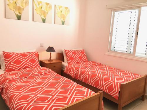 a bedroom with two beds and a window at Limnaria Westpark in Paphos