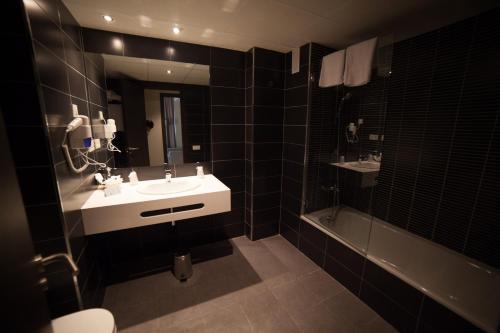 a bathroom with a sink and a mirror and a tub at Brea's Hotel in Reus