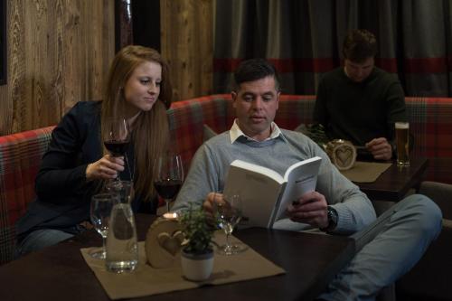 a man and a woman sitting at a table with a book at Tauferberg in Umhausen
