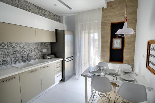 een keuken met witte kasten en een tafel en stoelen bij Cosmos n Armonia Apts.(Must) in Thessaloniki