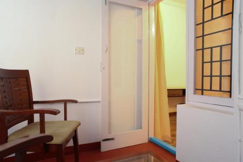 a room with a chair and an open door at Locul Uptown - Near Bangalore Palace Grounds in Bengaluru