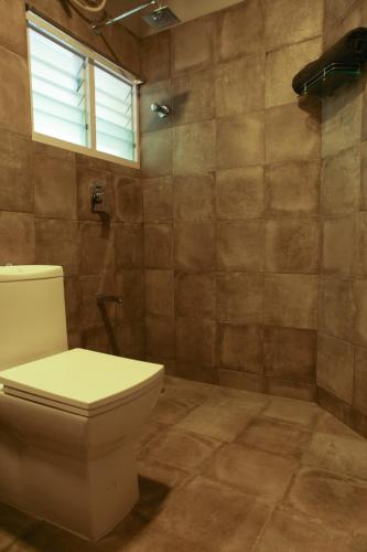 a bathroom with a toilet and a window at Locul Uptown - Near Bangalore Palace Grounds in Bengaluru