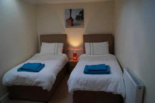 two beds in a small room with blue towels on them at Viking Villa in Broadstairs