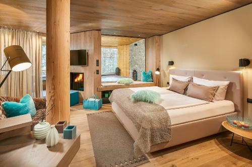 a bedroom with a large bed and a fireplace at Naturhotel Waldklause in Längenfeld