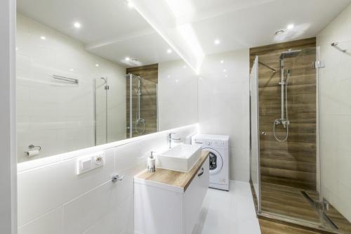 biała łazienka z umywalką i prysznicem w obiekcie Apartament Żeglarska U2 w mieście Giżycko