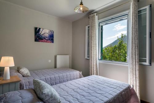 um quarto com 2 camas e uma grande janela em Ainos Retreat em Cefalônia