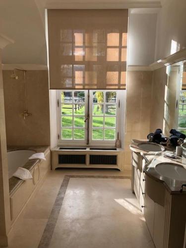 a large bathroom with two sinks and a window at Le domaine de barbizon in Saint-Martin-en-Bière