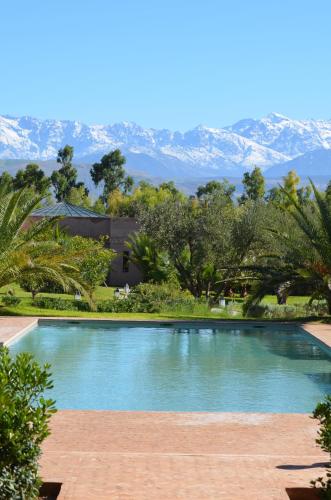 a swimming pool with mountains in the background at The Capaldi Hotel, Restaurant & Spa in Lalla Takerkoust