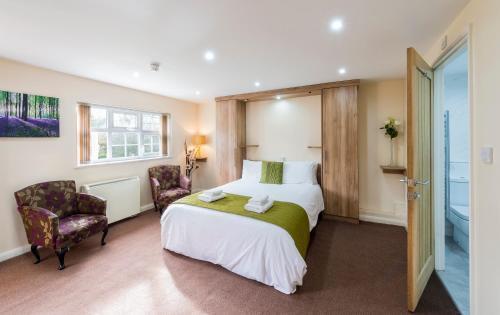 a hotel room with a bed and two chairs at The Limes Country Lodge Hotel & Admiral Restaurant in Solihull