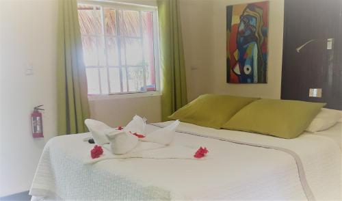 Una cama blanca con dos toallas y flores. en Paraiso Beach Hotel, en Isla Grande del Maíz