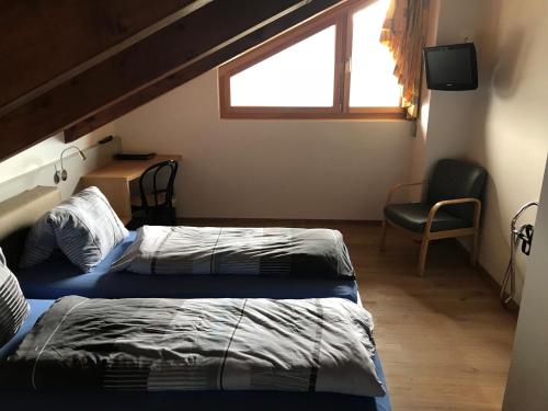 a bedroom with two beds and a chair and a window at Hotel Restaurant Kulm in Triesenberg