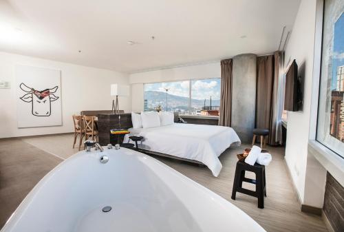 a bathroom with a bath tub and a bed at V Grand Hotel, a member of Radisson Individuals in Medellín