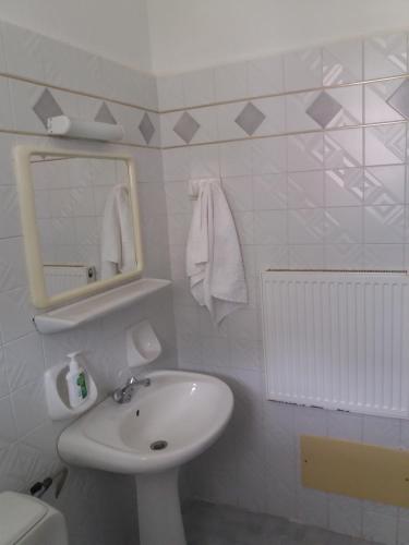 a white bathroom with a sink and a mirror at Heracles Hotel in Spílion