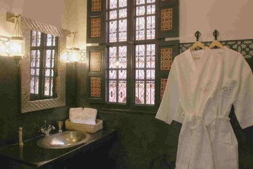 a bathroom with a sink and a white robe at Riad Altair in Marrakech