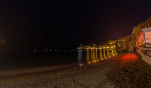 a beach at night with lights on the water at Hotel Miramare & Spa in Sestri Levante
