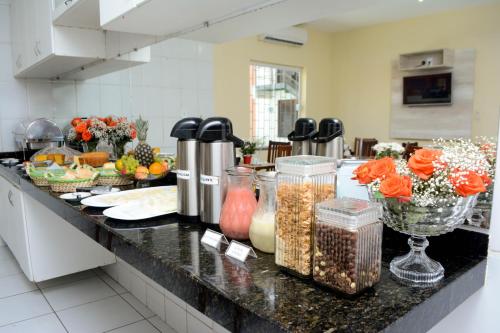 una cocina con una barra con comida y flores. en Hotel Sambaquis en São Luís