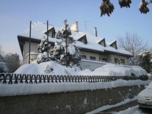 a house with a fence covered in snow at Panoráma Üdülőszálló in Sopron