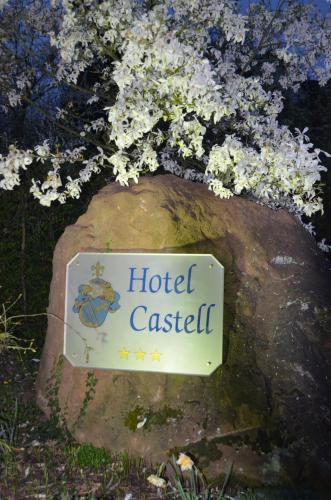 a sign for a hotel castel on a rock with flowers at Castell Hotel & Restaurant in Leinsweiler