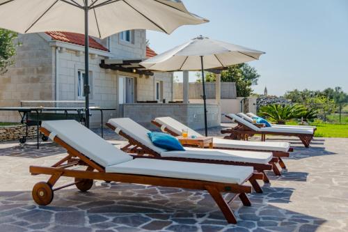 a row of lounge chairs and umbrellas on a patio at Villa Mis in Supetar