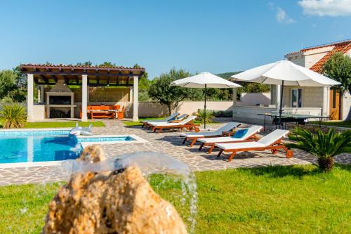 a pool with chairs and umbrellas next to a house at Villa Mis in Supetar