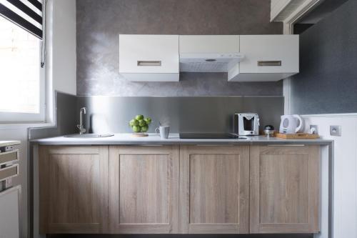 - une cuisine avec des placards en bois et des appareils blancs dans l'établissement Cosy Cottage, à Bourbourg