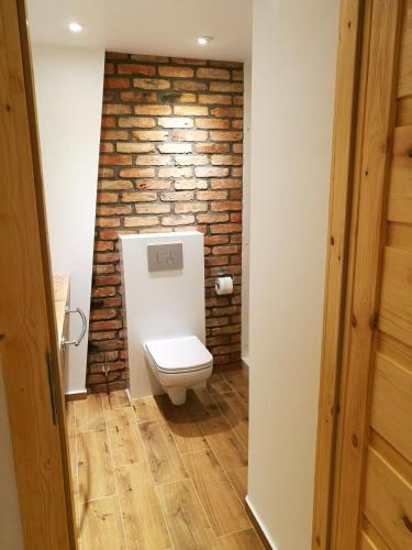 a bathroom with a brick wall and a toilet at Kamienica Na Nowo Apartamenty in Mrągowo