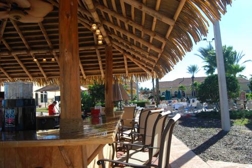 a wooden bar with chairs under a straw umbrella at Regal Palms Resort & Spa in Davenport