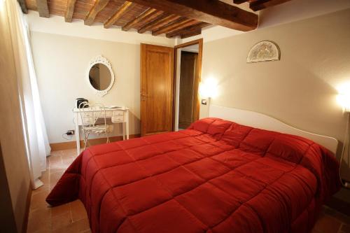 a bedroom with a red bed in a room at Mezzanino L Palazzo Gagnoni Grugni in Montepulciano