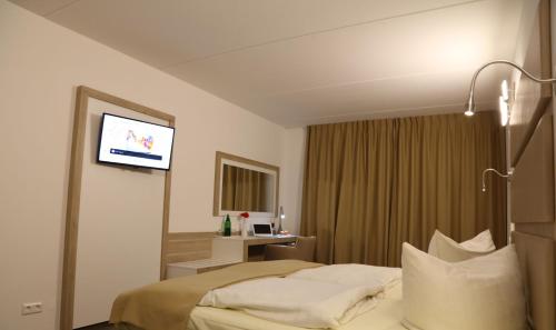 a hotel room with a bed and a flat screen tv at Confour Hotel in Burgdorf