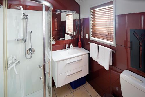 a bathroom with a white sink and a shower at Palm Waiheke Island Resort in Palm Beach