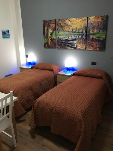 two beds in a room with two blue lights at foresteriareartu in Mortara