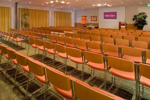 an empty lecture hall with orange chairs in it at Mercure Hotel Saarbrücken Süd in Saarbrücken
