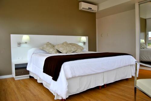 a bedroom with a large white bed with two pillows at Hotel Castilla in Punta del Este