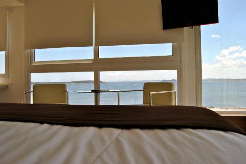 a bedroom with a bed and a large window at Hotel Castilla in Punta del Este